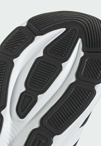 Close-up of white shoe sole with black rubber traction patterns featuring ridges and textured grip areas.