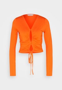 Orange långärmad topp med djup V-ringning, rynkad front, nyckelhålsdetalj och dragsko i nederkant. Tillverkad av stretchigt material för en figurnära passform.