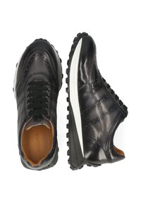 Czarne skórzane sneakersy z detalami w stylu brogue, okrągłym noskiem, czarnymi sznurowadłami i białą gumową podeszwą z teksturowanym wzorem antypoślizgowym.