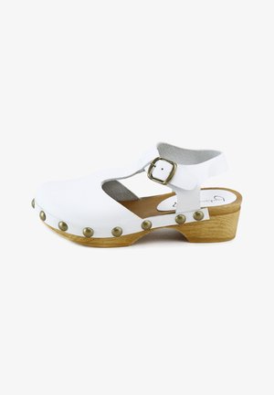Sandalia blanca de cuero estilo zueco con correa ajustable con hebilla, tachuelas de latón y tacón bajo de madera, vista desde el lado exterior.