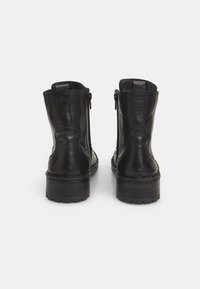 Botine negre din piele cu fermoar, vârf rotund, suprafață texturată și toc mic cu talpă robustă, profilată.
