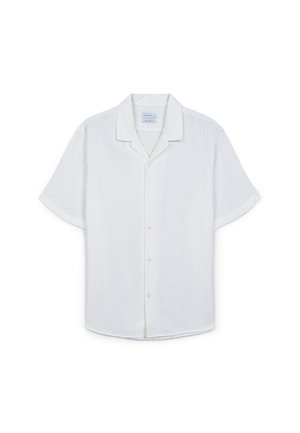 Chemise blanche à manches courtes, boutonnée, en tissu texturé avec un motif géométrique subtil et un col classique.