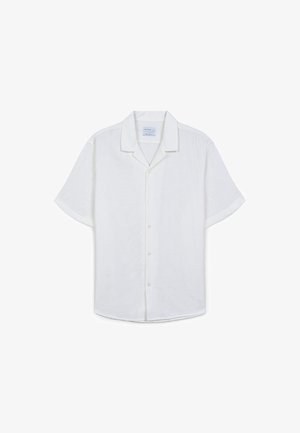 Camicia bianca a maniche corte con bottoni, realizzata in un tessuto testurizzato e caratterizzata da un sottile motivo geometrico e un colletto classico.