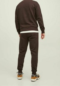 Brun sweatshirt och joggers-set i mjukt tyg, med ribbade ärmslut och slim fit, kombinerat med sneakers i neutrala färger.