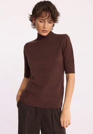 Sweter z krótkim rękawem i wysokim dekoltem w ciemnym brązie, wykonany z miękkiego materiału. Posiada ściągacze na rękawach i dolnym brzegu oraz luźny krój.