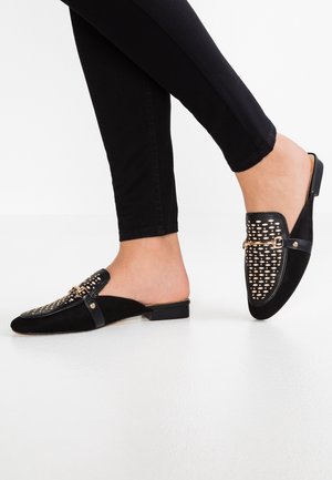 Black velvet slip-on shoes with a woven detail and gold hardware accents. Low block heel and smooth sole.