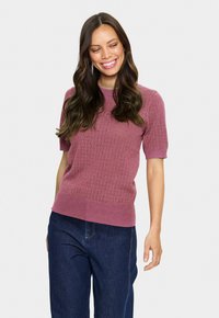 Kurze Ärmel, tailliertes Sweater in Mauve mit strukturiertem Rautenmuster. Abgerundet mit einem festen, gerippten Saum und Rundhalsausschnitt. Kombiniert mit dunklen Jeans.