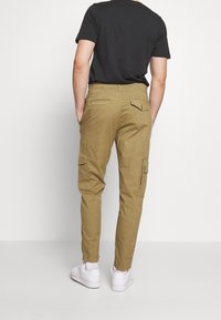 Kahaki cargo broek met taps toelopende pijpen, twee zijzakken en twee achterzakken. Het materiaal lijkt lichtgewicht met een soepele textuur.