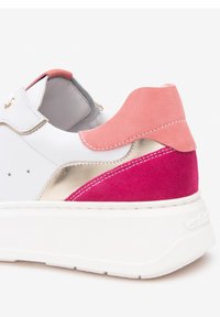 Baskets blanches avec un accent de talon en daim rose et des détails métalliques dorés. Semelle texturée avec un contrefort blanc prononcé et des coutures contrastantes.