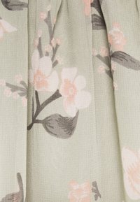 Pehmeän vihreä kukkakuvioinen kangas, jossa vaaleanpunaisia ja harmaita kukkia. Kevyt, teksturoitu materiaali, jossa on hieman läpikuultava ilme.