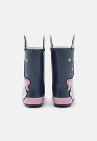 Mörkblå barnregnstövlar med rosa sulor, dekorationer av enhörningar och stjärnor, och regnbågsfärgade dragband högst upp, visade från baksidan.