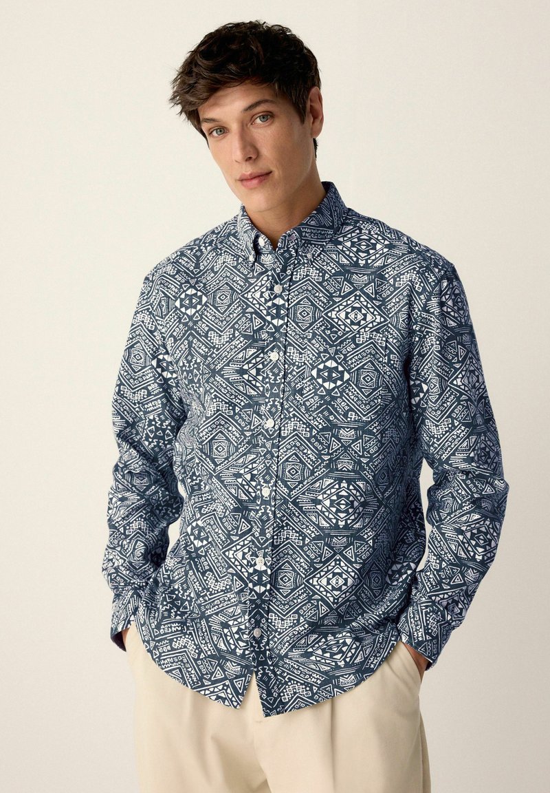 Langärmliges Hemd mit Knöpfen, das ein blau-weißes geometrisches Muster aufweist, aus leichtem Stoff mit klassischem Kragen und lockerer Passform.