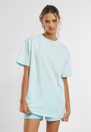 Ljusblå t-shirt med vita vertikala ränder, korta ärmar, rund halsringning och subtil logotypdetalj på bröstet. Avslappnad passform.