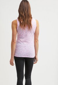 Top sin mangas de estampado de leopardo rosa, hecho de tela suave, con un diseño ajustado, escote redondeado y textura lisa. Combinado con leggings negros.
