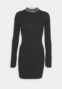 Robe noire en tricot côtelé à manches longues, silhouette ajustée, col blanc avec le logo Calvin Klein Jeans répété.