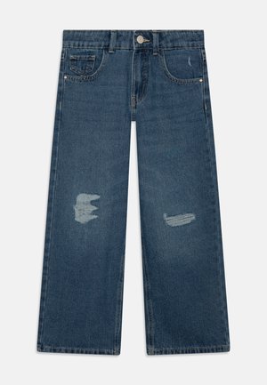 Blaue Jeans mit weitem Bein und abgenutzten Patches an beiden Beinen, Vordertaschen, Gürtelschlaufen und einem Knopfverschluss an der Taille.