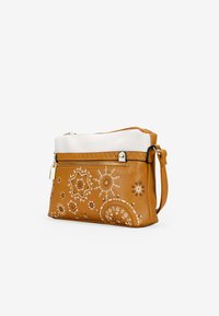 Bolso de mano de cuero marrón con parte superior blanca, patrones decorativos cosidos y cierre con cremallera. Correa de hombro desmontable y herrajes en tono dorado.