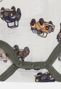 Bodysuit de algodón con un fondo crema y coloridas ilustraciones de coches al revés, bordeado con un ribete verde oscuro y cierres a presión.