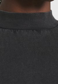 Schwarzes Oberteil mit hohem Kragen aus geripptem Stoff, mit einer strukturierten Oberfläche und tailliertem Schnitt, ideal zum Layering.
