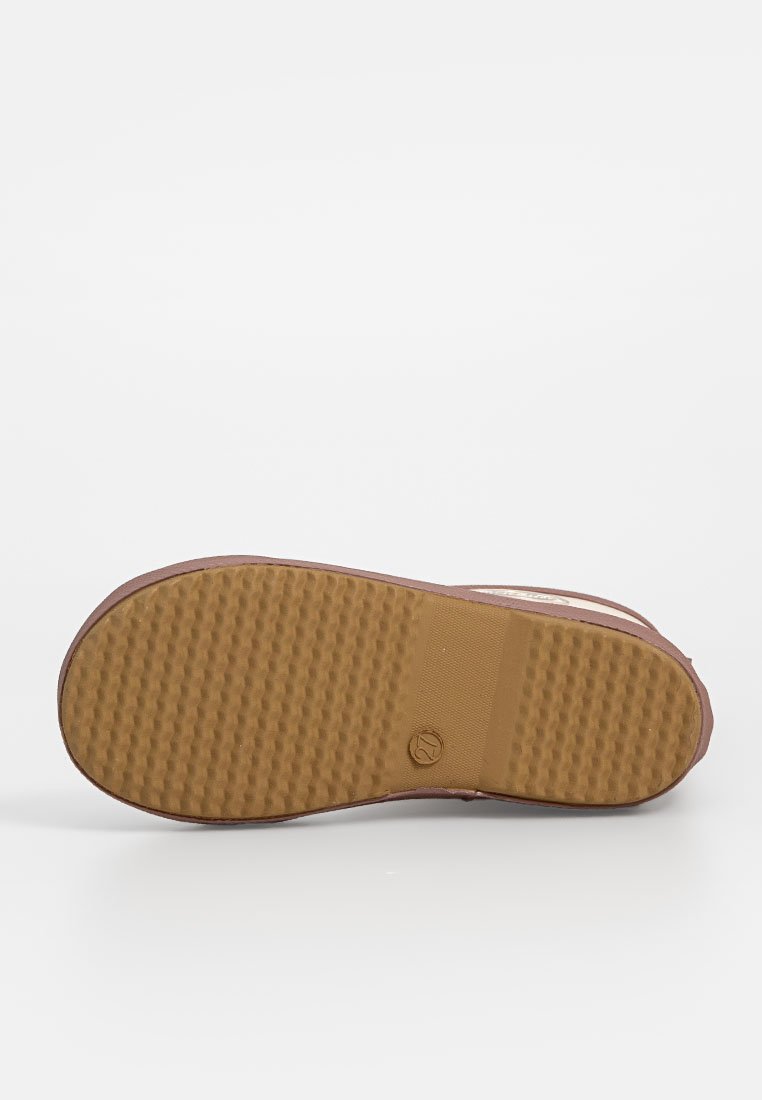 Suola di una sneaker marrone e beige che mostra una suola in gomma testurizzata con un piccolo logo circolare vicino al centro.