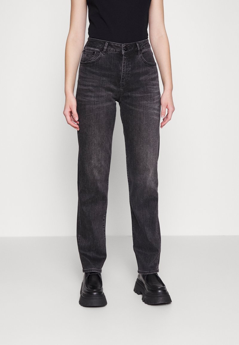 Vaqueros de mezclilla negra con cintura alta, pierna recta y costuras visibles. Tienen bolsillos frontales y un cierre con botones.