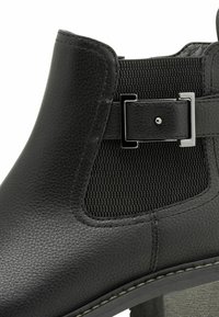 Black ankle boot with a smooth leather upper, textured side panel, silver buckle detail, and a chunky heel.