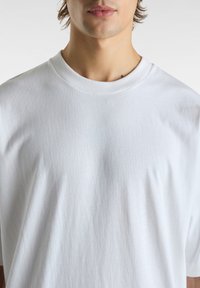 Bílý crew neck tričko vyrobené z měkké bavlny, s volným střihem, krátkými rukávy a bez viditelných vzor�ů nebo akcentů.