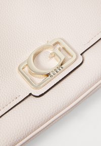 Borsa a mano in pelle textured rosa chiaro con accentuazione del logo G dorato e rifiniture nere. Il design presenta cuciture senza giunte lungo i bordi.