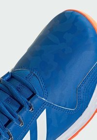 Niebieski but sportowy z teksturowaną, wzorzystą cholewką. Posiada niebieskie sznurówki, białe akcenty oraz pomarańczową podeszwę.