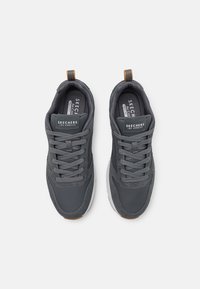 Gray athletic shoes featuring a textured upper, lace-up design, memory foam insole, and contrasting brown accents on the heel.