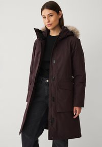 Bordeaux parka met nep bont gevoerde capuchon, ritssluiting aan de voorkant en drukknoopsluitingen. Voorzien van voorzakken en een waterdichte, gestructureerde stof.