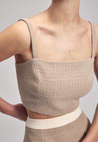 Beige textuur crop top met vierkante halslijn en dunne bandjes, met een aansluitend ontwerp en contrasterende crèmekleurige tailleband.