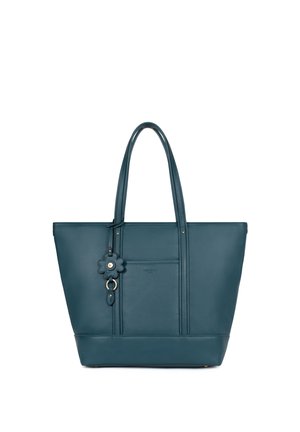 Sac fourre-tout en cuir bleu sarcelle avec double poignées et un porte-clé en forme de fleur suspendu à une des poignées sur fond blanc.