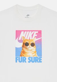 Balts kokvilnas T-krekls ar grafisko attēlu, kurā redzams kaķis saulesbrillēs. Teksts "NIKE FUR SURE" izceļas spilgtās krāsās uz rozā un zilā fona.