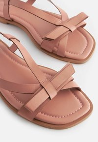 Rosa Leder-Flatsandalen mit einem Kreuzband-Design, quadrater Zehenpartie und genähten Details auf der Sohle.