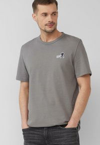 Szary bawełniany t-shirt z okrągłym dekoltem, z małym czarno-białym logo graficznym na piersi, krótkimi rękawami i luźnym krojem.