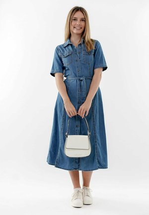 Vestido de camisa de mezclilla con cintura ajustada, mangas cortas y botón frontal. Combinado con un bolso blanco y zapatillas blancas. Textura suave.