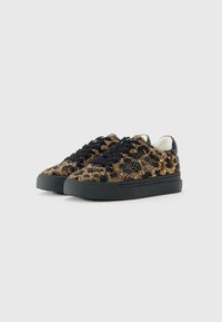 Une paire de baskets basses avec des semelles noires, des lacets noirs et des embellissements en imprimé léopard doré et noir.