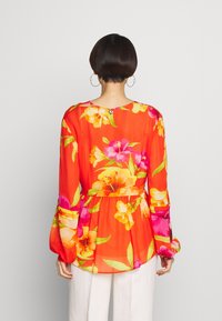 Bloemblouse in helder oranje met lange, opgeblazen mouwen. Bevat grote, meerkleurige bloemen en een getailleerde taille. Lichtgewicht stof.