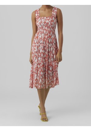 Sukienka midi w różowo-białym kwiatowym wzorze, z marszczonym gorsetem, warstwową spódnicą i falbaniastymi ramiączkami. W połączeniu z żółtymi obcasami.