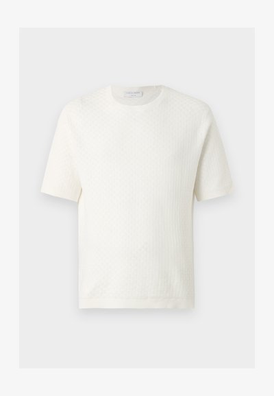Άσπρο πλεκτό πουλόβερ με κοντά μανίκια, απαλή υφή και στρογγυλή λαιμόκοψη, εμφανίζεται σε απλό ανοιχτό φόντο.