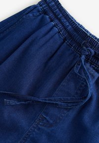 Marinblå kordflorshorts med elastisk midja och snörning, med vertikal ribbad textur och en sidoficka.