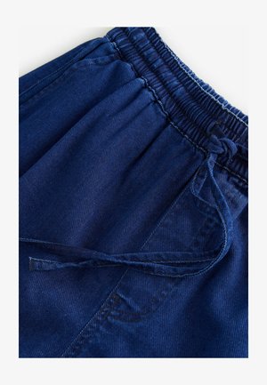 Tumši zilas korduroja šortus ar elastīgu jostu un aukliņu, ar vertikālu ribotu tekstūru un sānu kabatu detaļu.