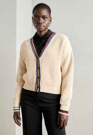 Knit cardigan'as grietinės spalvos su V formos iškirpte, puošniu daugiaspalviu apvadu aplink apykaklę ir rankogalius. Detalėse – penki mygtukai priekyje.