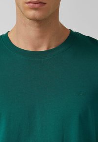 T-shirt verde in cotone con scollo rotondo, maniche corte e logo s.Oliver in nuance. Tessuto liscio, vestibilità classica.