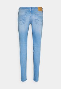 Vaqueros ajustados de color azul claro con cintura alta, bolsillos traseros y una tela vaquera texturizada con un desvanecimiento sutil. Incluyen una etiqueta marrón en la cintura.