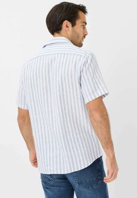 Camicia a maniche corte, blu chiaro con strisce verticali bianche, colletto button-down, tessuto morbido, orlo leggermente curvo, vista posteriore.