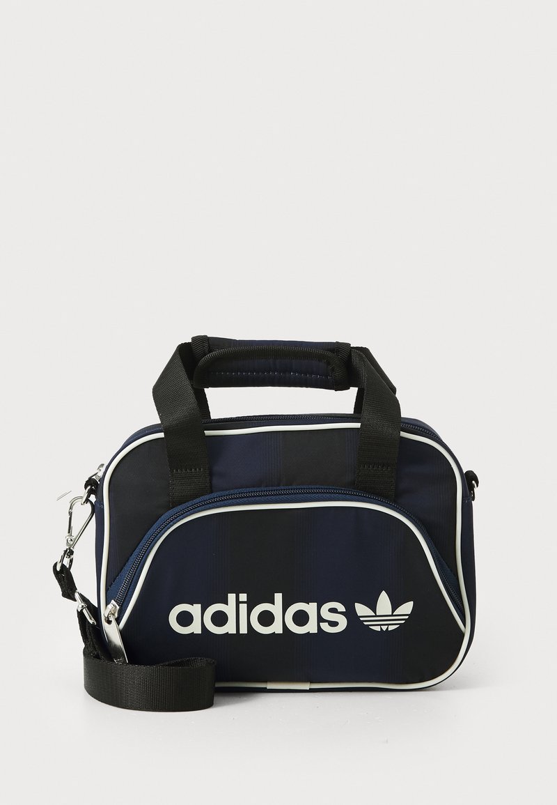 Navy blue Adidas bag with black handles, white accents, and logo. Features a zip closure and a detachable shoulder strap. Textured fabric.