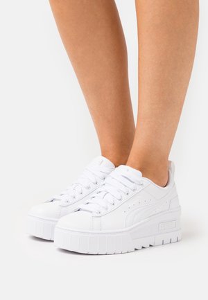 Weiße Plattform-Sneaker mit einer glatten Synthetik-Oberfläche, runder Zehenpartie und dicker Gummisohle. Zu den Merkmalen gehören eine Schnürung und ein Logo an der Seite.
