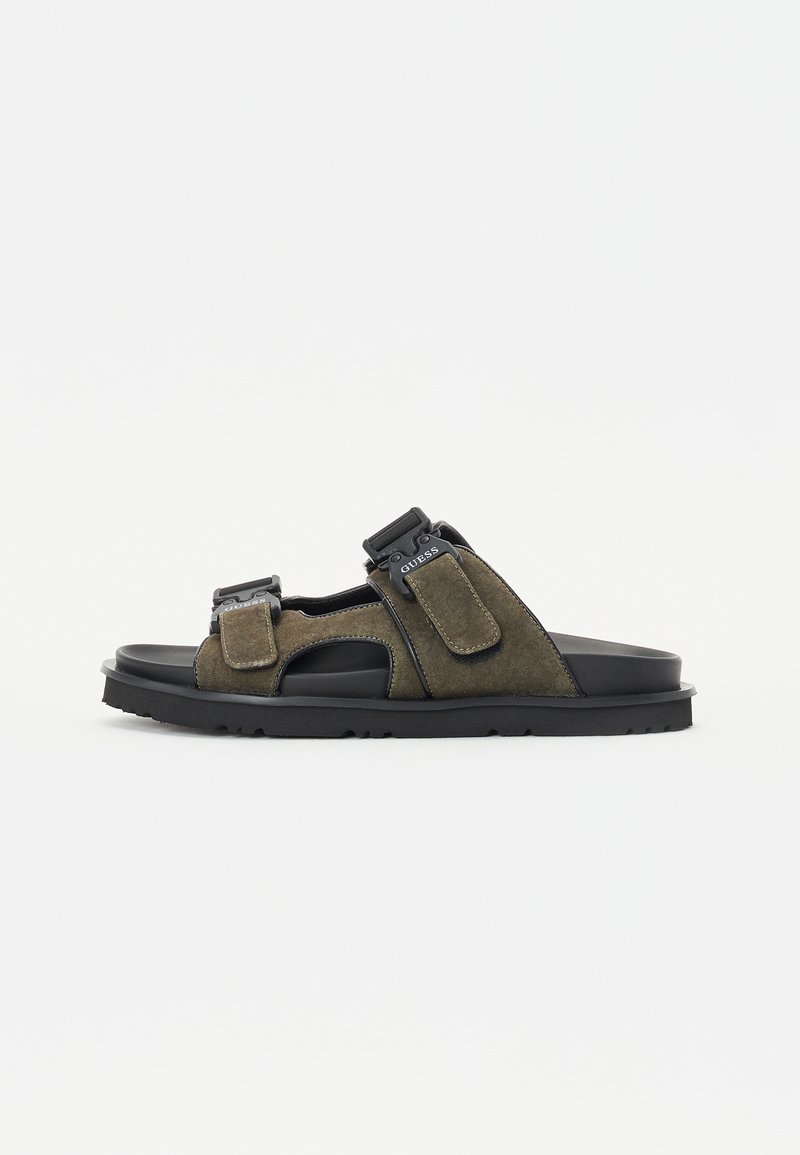 Barna velúr szandálok nyitott dizájnnal, dupla állítható pánttal, fekete gumitalppal és kontrasztos varrási részletekkel.